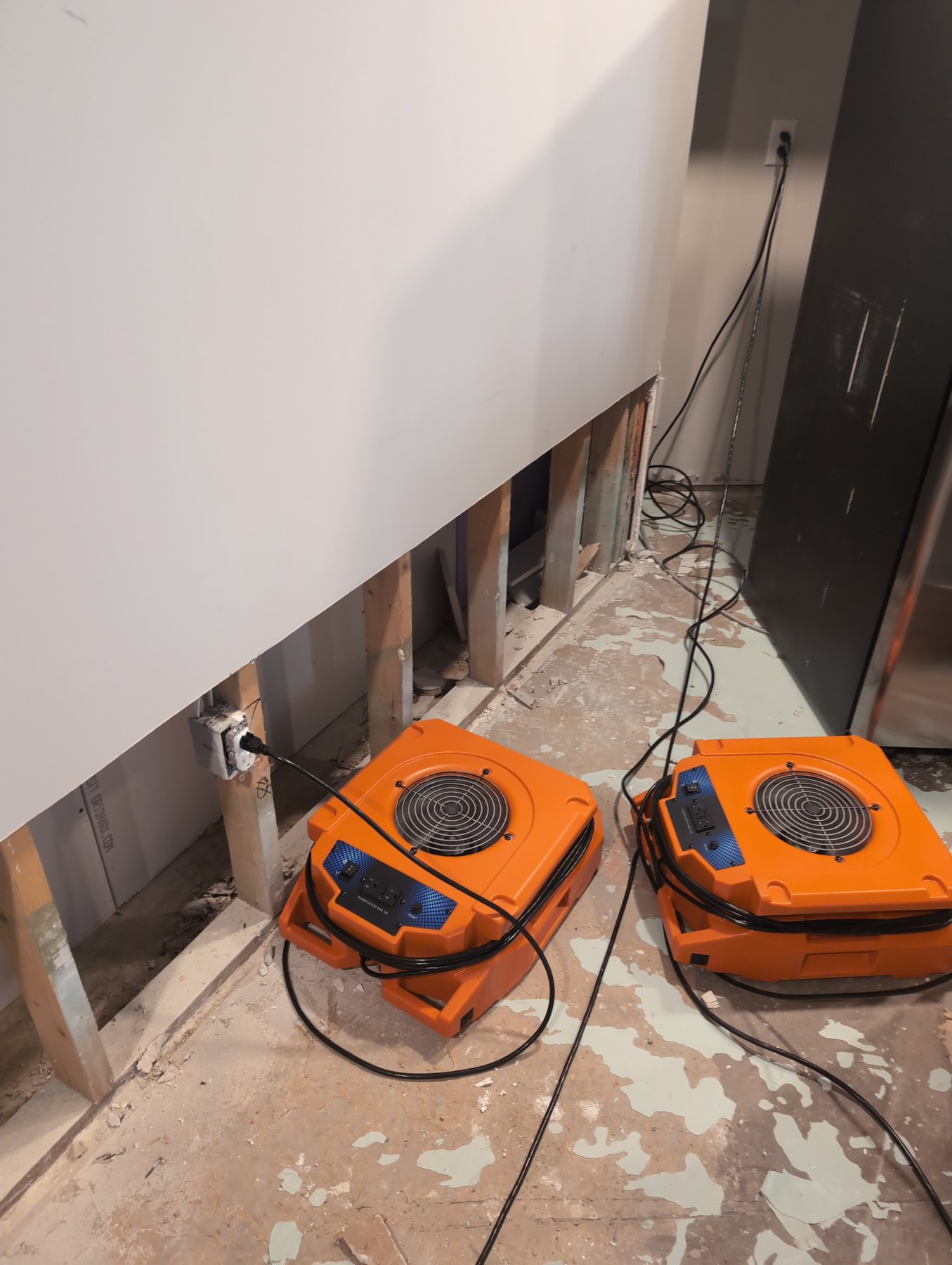 Air movers drying an apartment after a flood cut, with drywall removed two feet above the floor