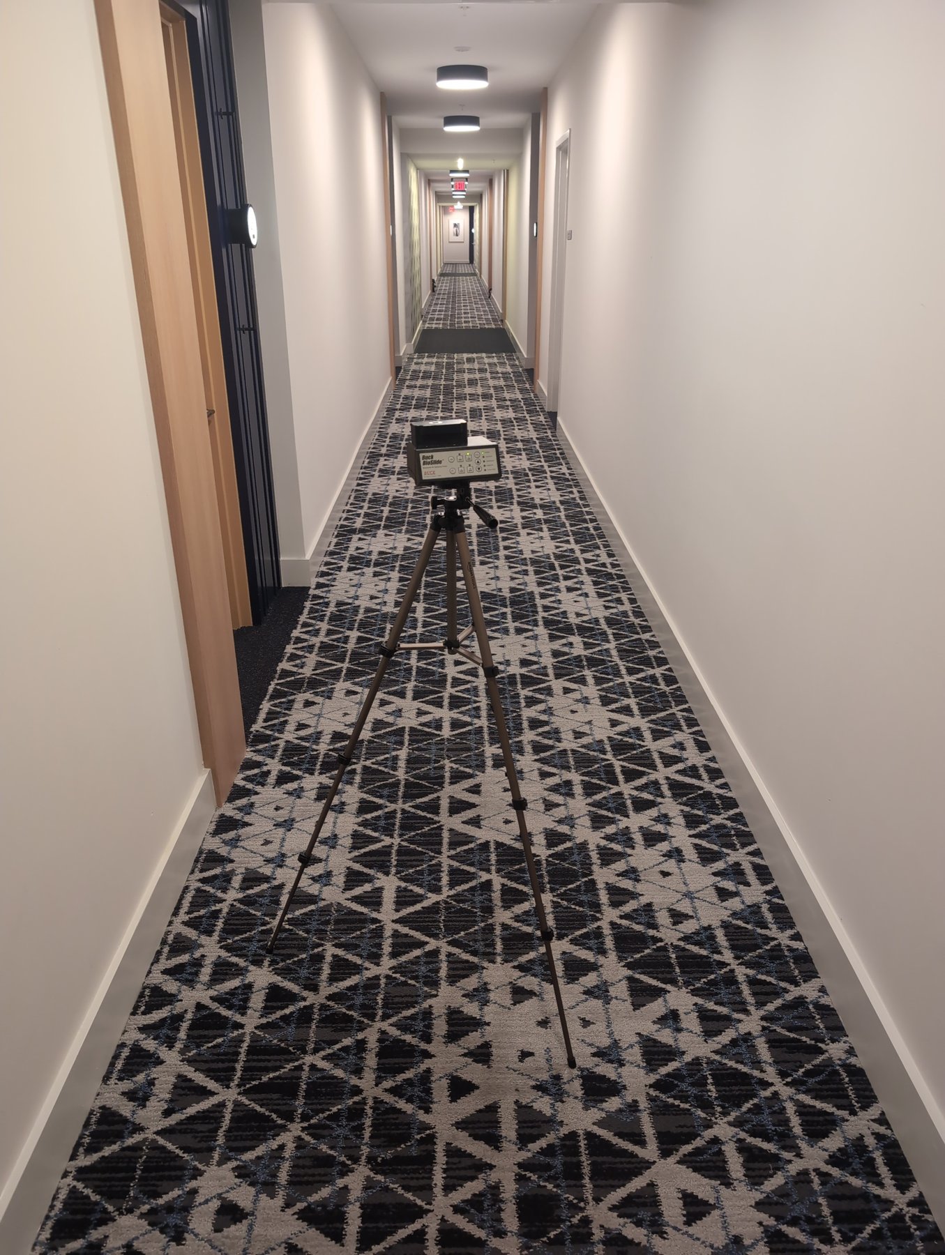 Buck BioSlide spore trap air sampling pump on a tripod in a hotel corridor during mold clearance testing