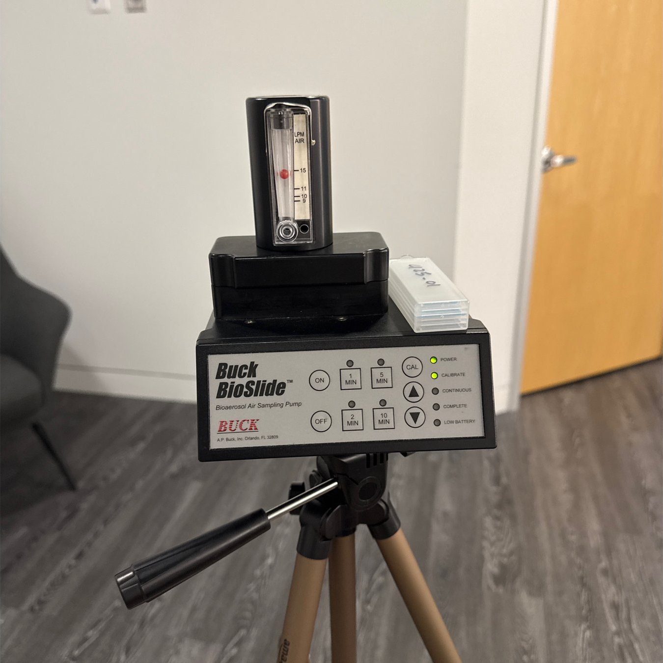 Buck BioSlide spore trap air sampling pump on a tripod collecting a mold air sample in an office