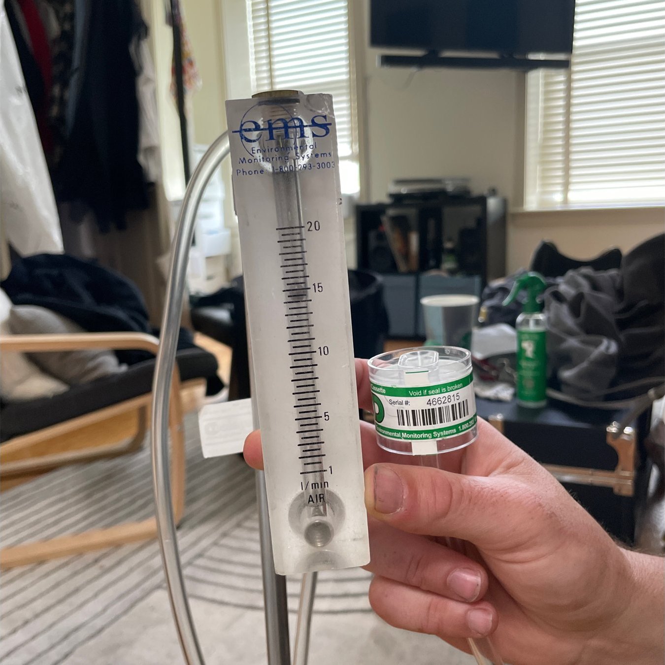 Inspector calibrating an asbestos air sampling pump with a rotameter, sampling cassette attached, before PCM air monitoring