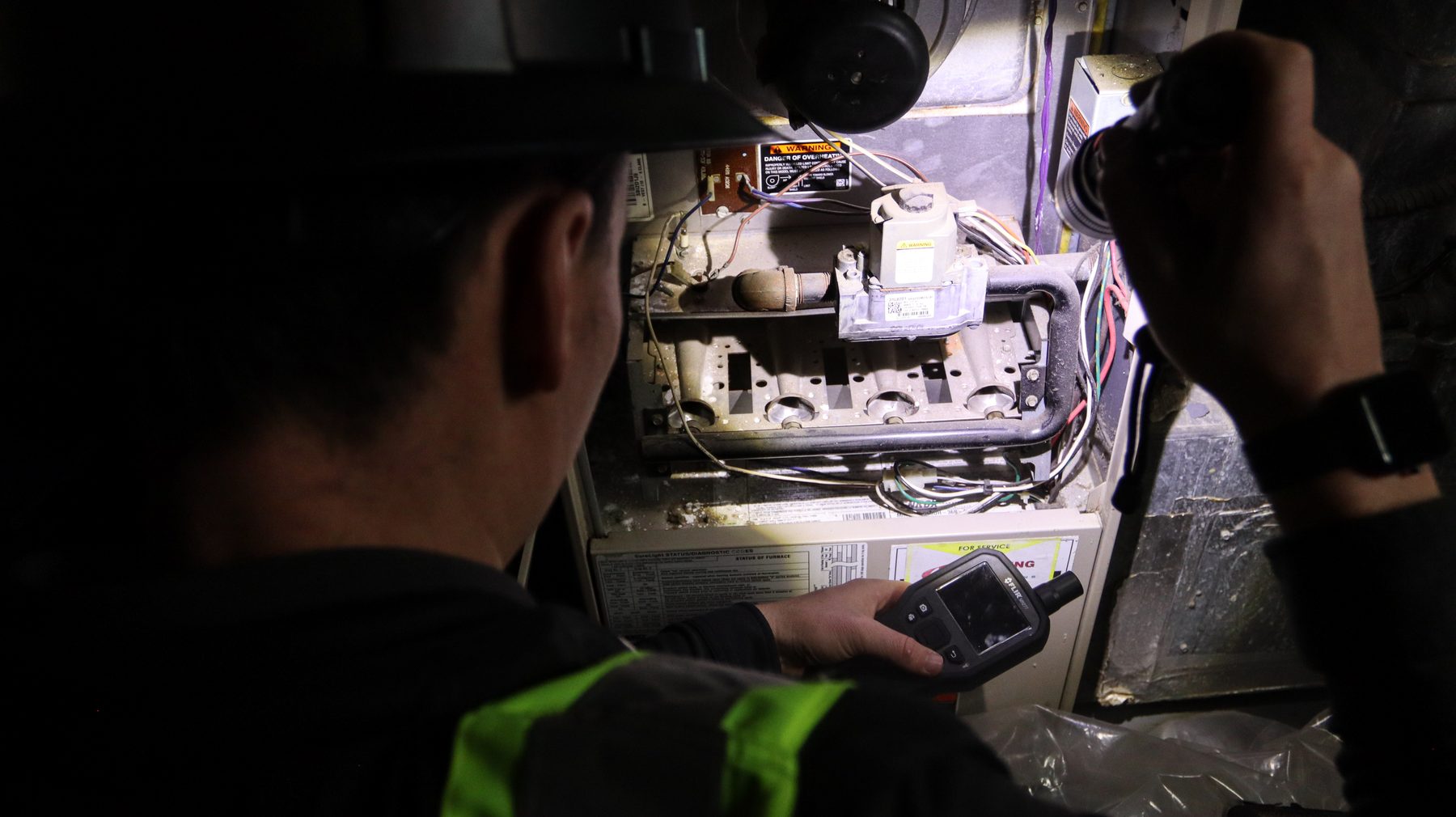 Inspector examining the inside of an air handling unit with a flashlight during an HVAC mold assessment