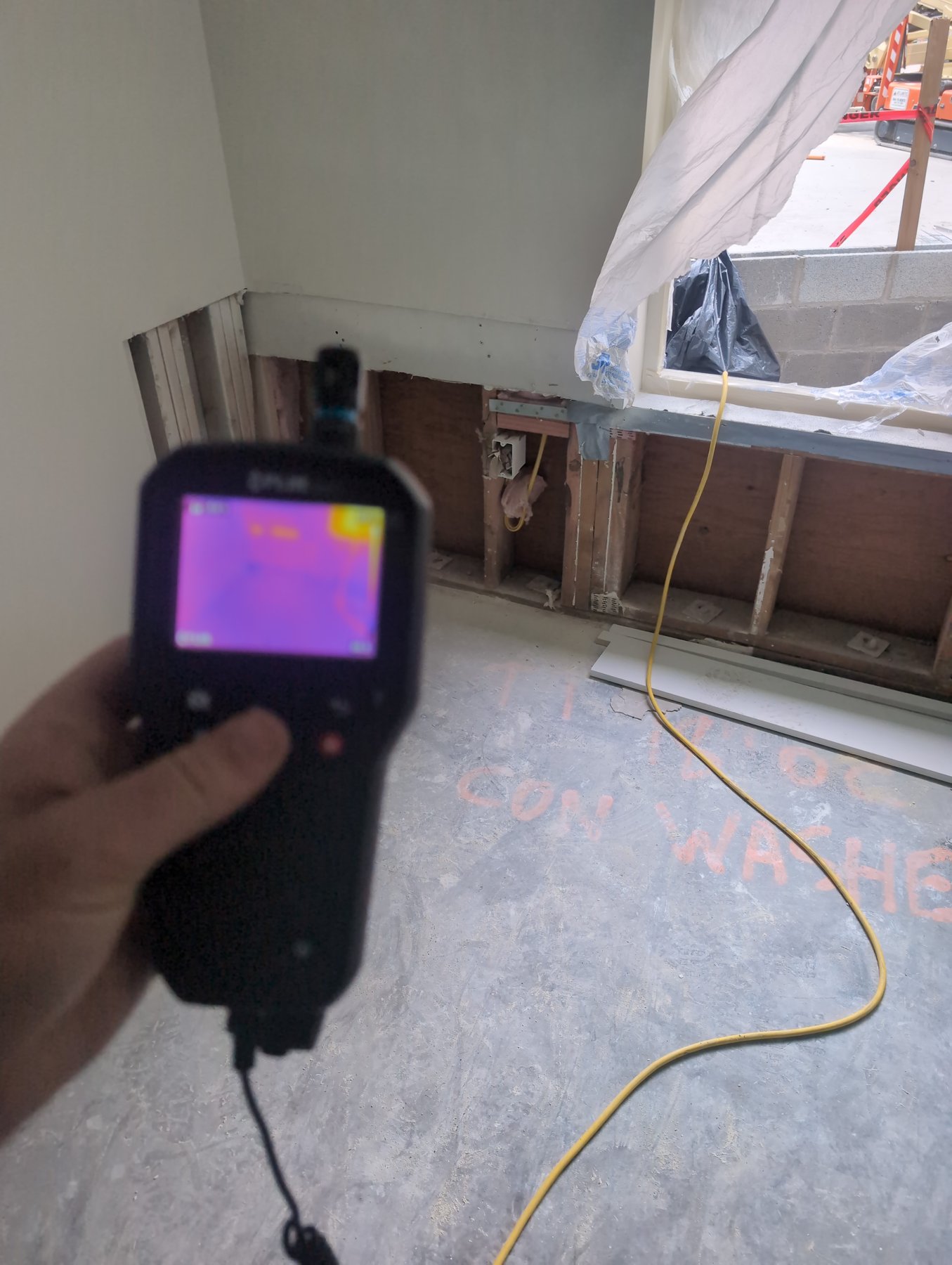 Inspector using a FLIR thermal camera on an opened wall during a moisture management inspection at The Chasen Apartments