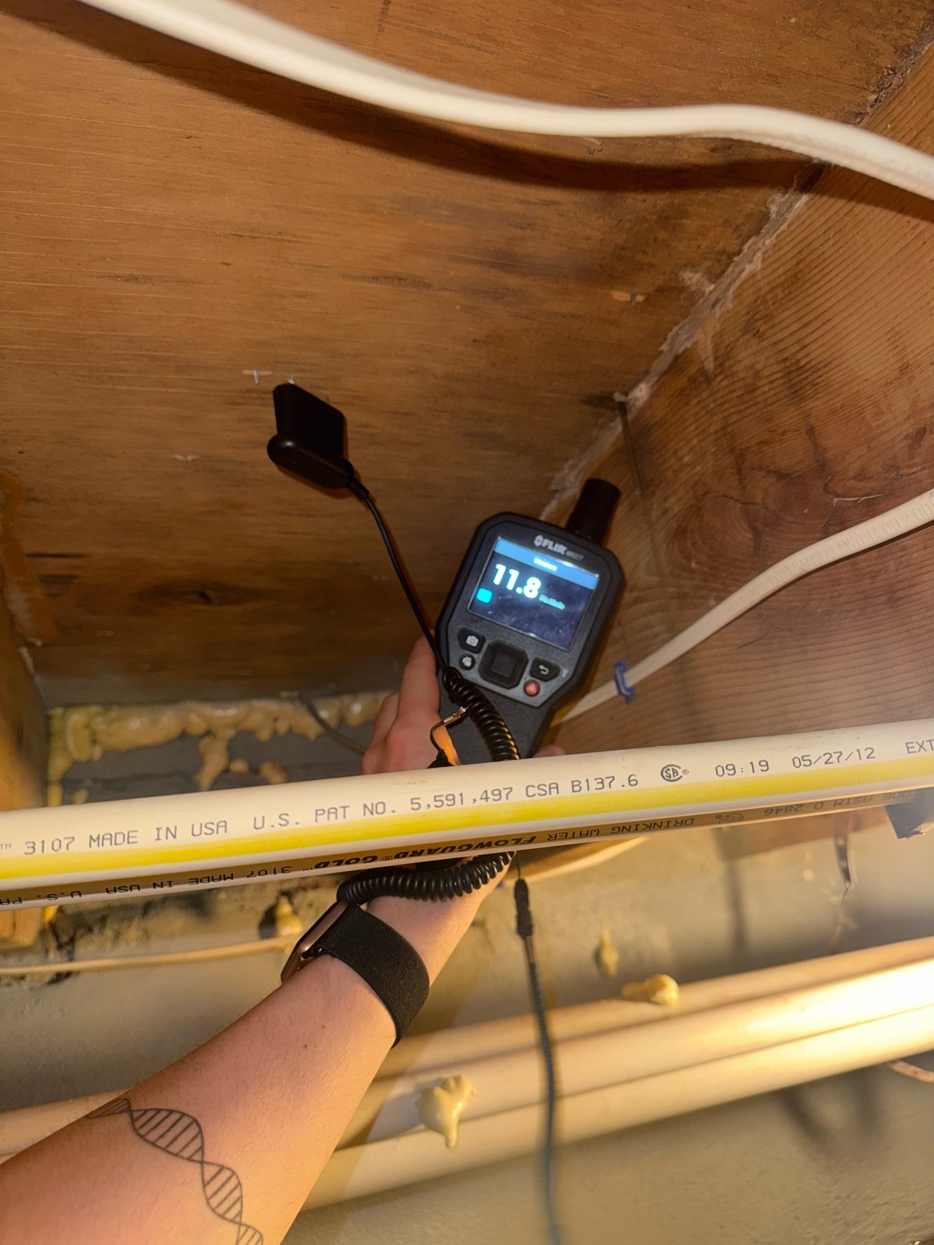 Prescient Environmental inspector taking a pin moisture reading on floor framing in a crawlspace