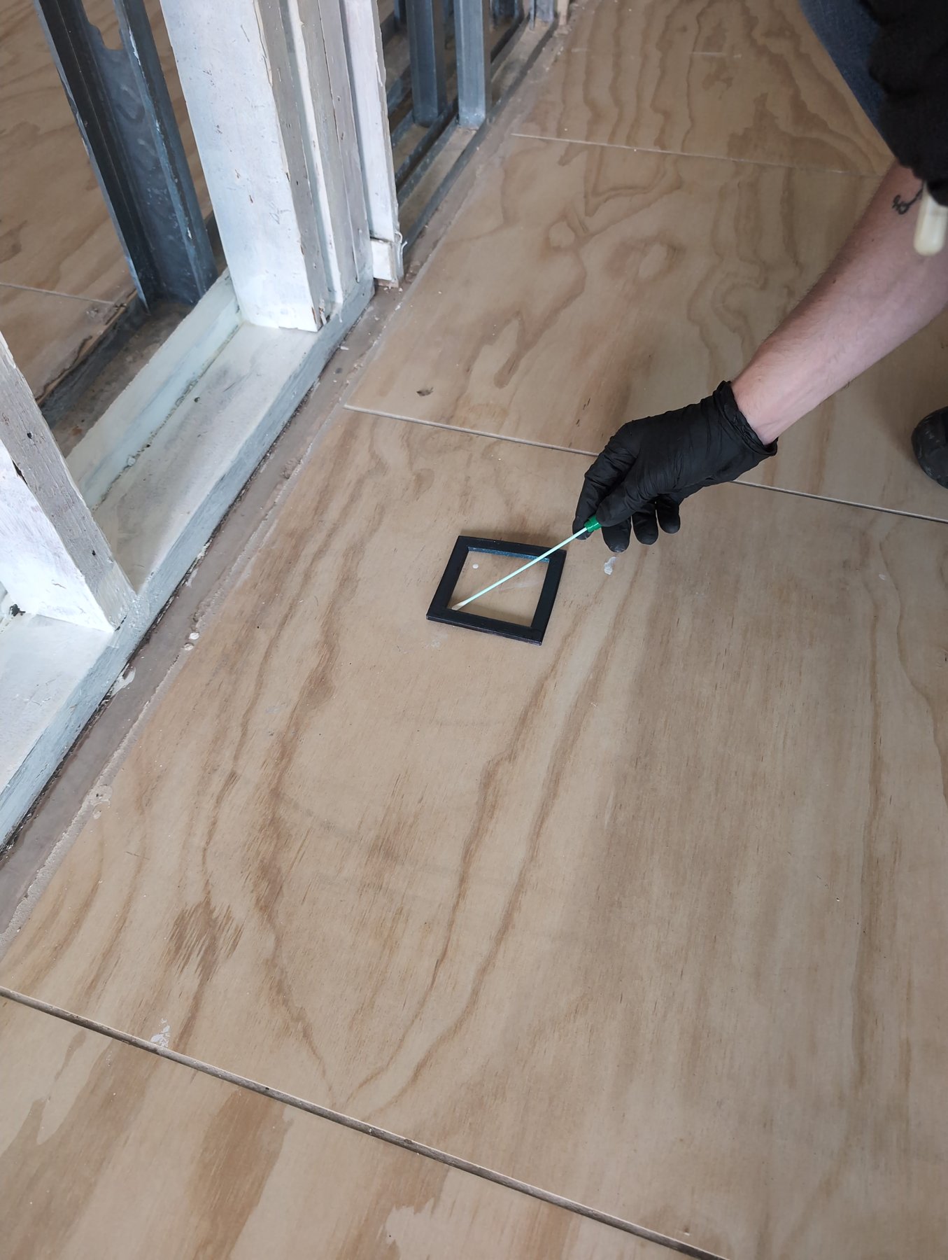 Gloved Prescient Environmental inspector swab sampling a floor with a sampling template after hurricane sewage flooding