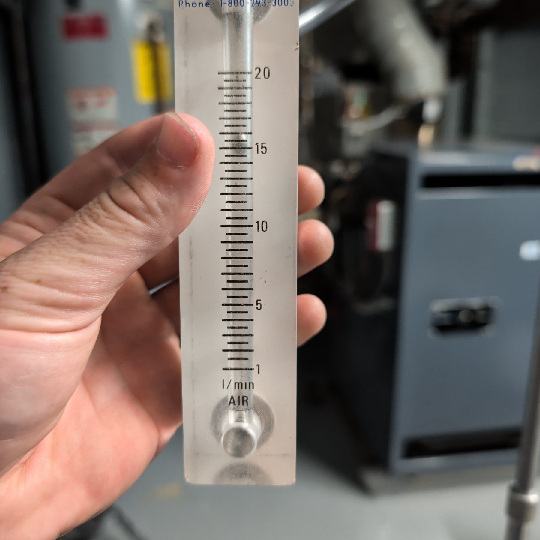Rotameter flow check on an air sampling pump in a basement mechanical room during asbestos air monitoring