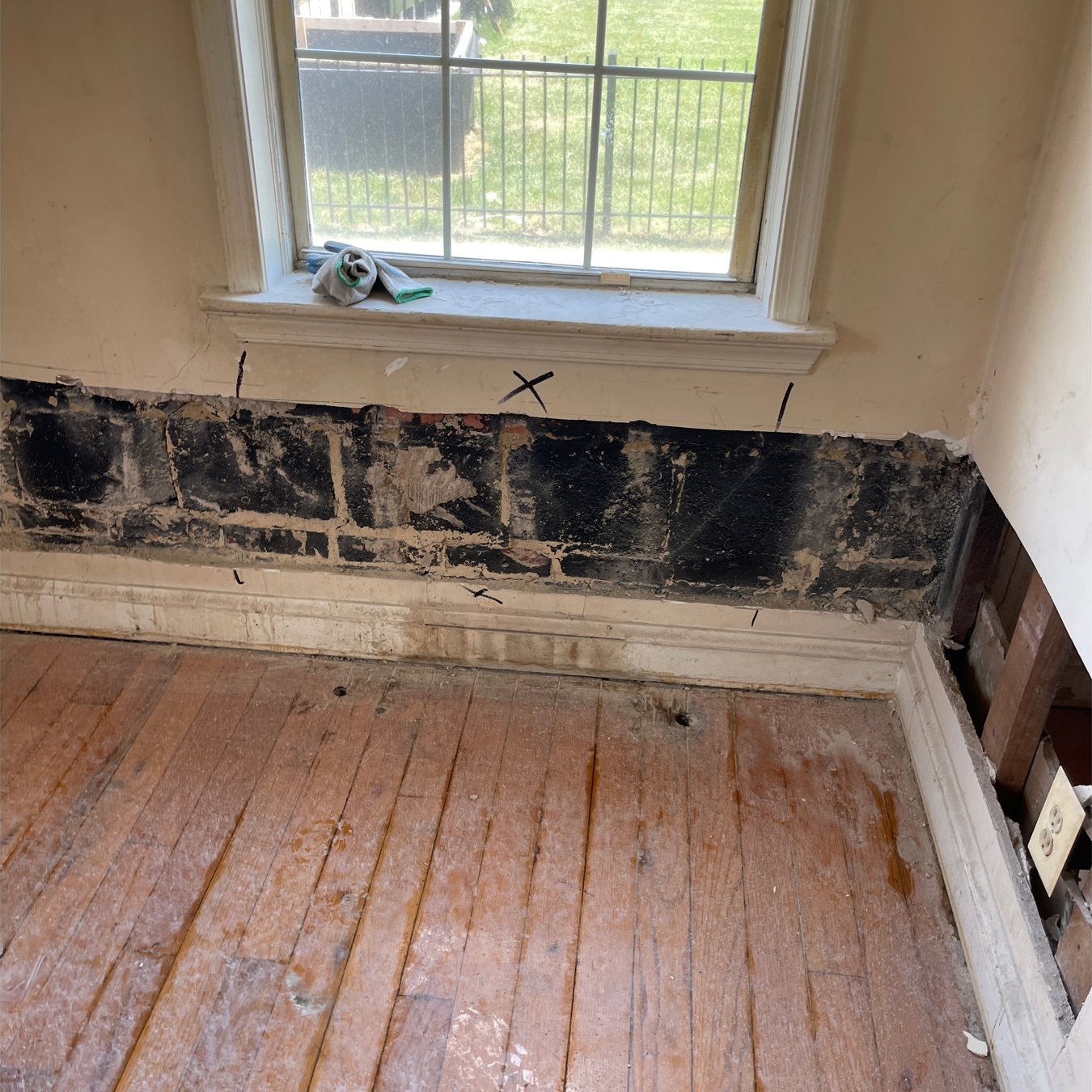 Apartment room at Worthington Woods with the lower drywall removed, revealing mold on the wall cavity under the window